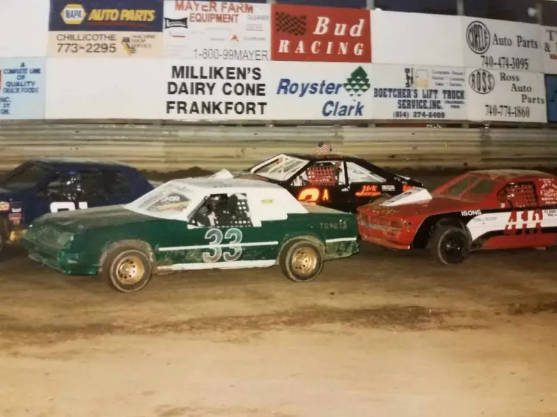 Vintage photo of stock cars racing in front of the old sign wall at 35 Raceway Park